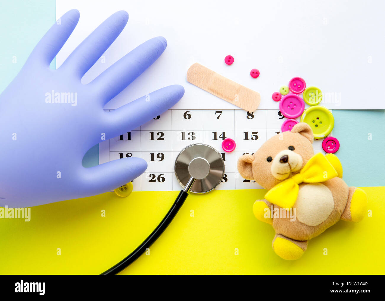 Children`s doctor appointment date number concept. Calendar with numbers, doctor, kids toys, pink and green buttons. Flat lay view. Stock Photo